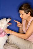 Woman reprimanding  white dog.