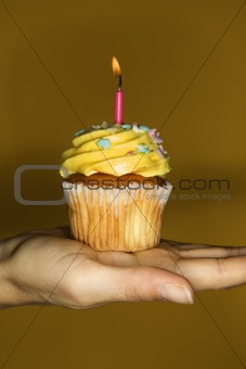 Woman's hand holding cupcake.