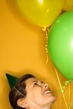 Woman wearing party hat with balloons.