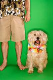 Man standing with dog wearing lei.