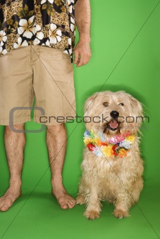 Man standing with dog wearing lei.