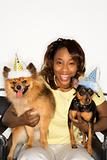 Woman holding dogs wearing party hats.