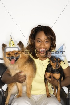 Woman holding dogs wearing party hats.