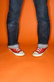 Person in jeans and sneakers with feet turned inward.