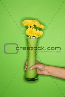 Woman's hand holding vase with flowers.