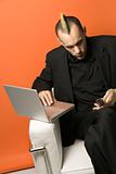 Businessman with mohawk on laptop and cellphone