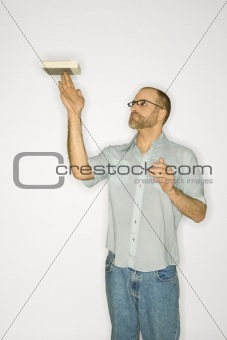 Caucasian man balancing book on finger.