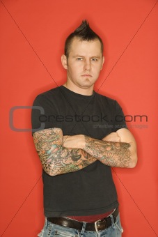 Caucasian man with mohawk and tattoos.