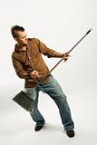 Caucasian man playing broom like guitar.