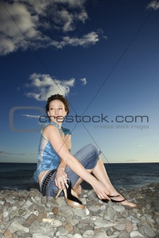 Adult female sitting on rocky shore.