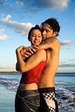 Young adult couple embracing on beach.