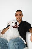 Young Caucasian man holding white dog on lap.