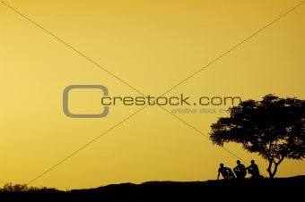  silhouette of three man sitting beside a tree in sunset