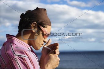 Young Man on Beach Lighting a Cigarette