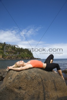Attractive Young Woman Lying on Rock at Beach
