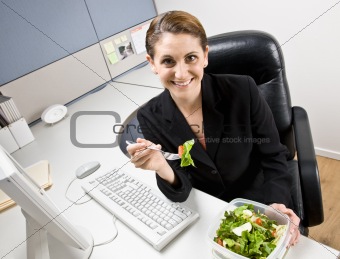 Businesswoman eating salad at desk