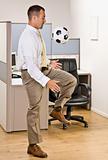 Businessman playing with soccer ball in office