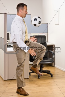 Businessman playing with soccer ball in office