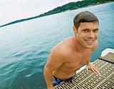 Man climbing onto pier from lake