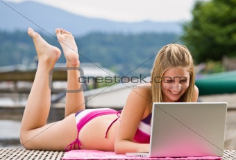 Woman laying on pier using laptop