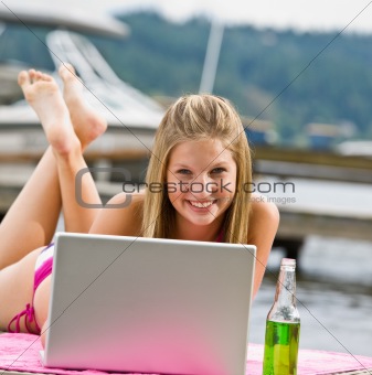 Woman laying on pier using laptop