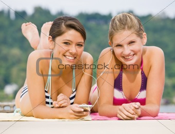 Friends laying on pier listening to mp3 player