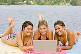 Friends laying on pier using laptop