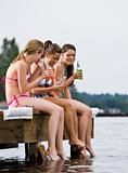 Friends sitting on pier at lake drinking soda