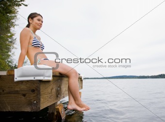 Woman sitting on pier at lake