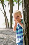 Boy hiding behind tree