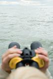 Person Looking Across Water Through Binoculars