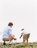 Father and son gathering rocks at beach