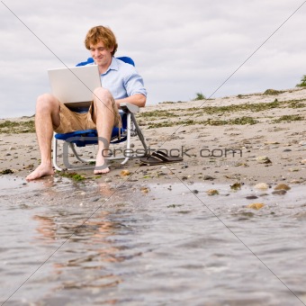 Man using laptop at beach