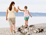 Mother helping daughter walk on log at beach