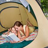 Mother reading to daughter in tent
