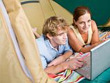 Couple laying in tent using laptop