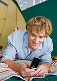 Man in tent text messaging on cell phone