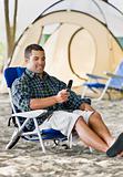 Man text messaging on cell phone at campsite