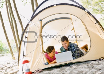 Couple laying in tent using laptop