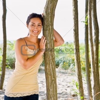 Woman leaning on tree at beach