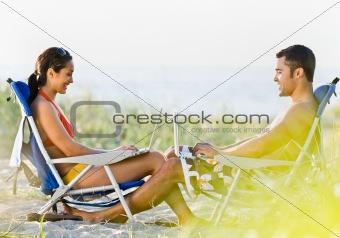 Couple using laptops at beach