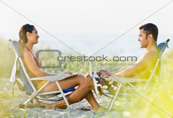 Couple using laptops at beach