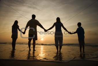 Family Holding Hands on Beach Watching the Sunset