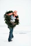 Man Carrying Wreath Through Snow