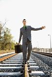 Businessman Walking on Railroad Tracks