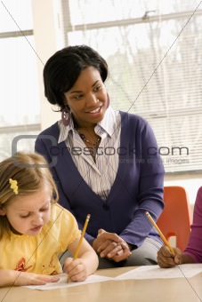 Teacher Smiling and Helping Students With Schoolwork 