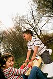 Young Girl and Boy Playing on Seesaw