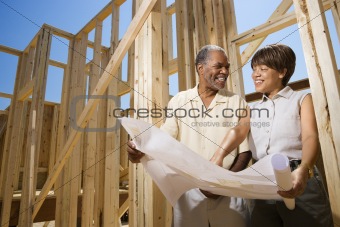 Couple Holding Building Plans on Construction Site