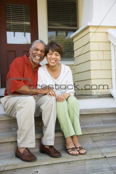 Couple Sitting on Outdoor Steps of Home Smiling