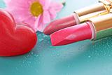 Two new lipsticks and pink flower on blue background